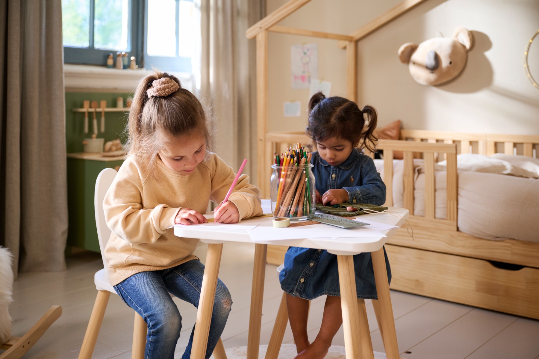 Enfants dessinant et manipulant des crayons à une table, développant la motricité fine et la précision des gestes