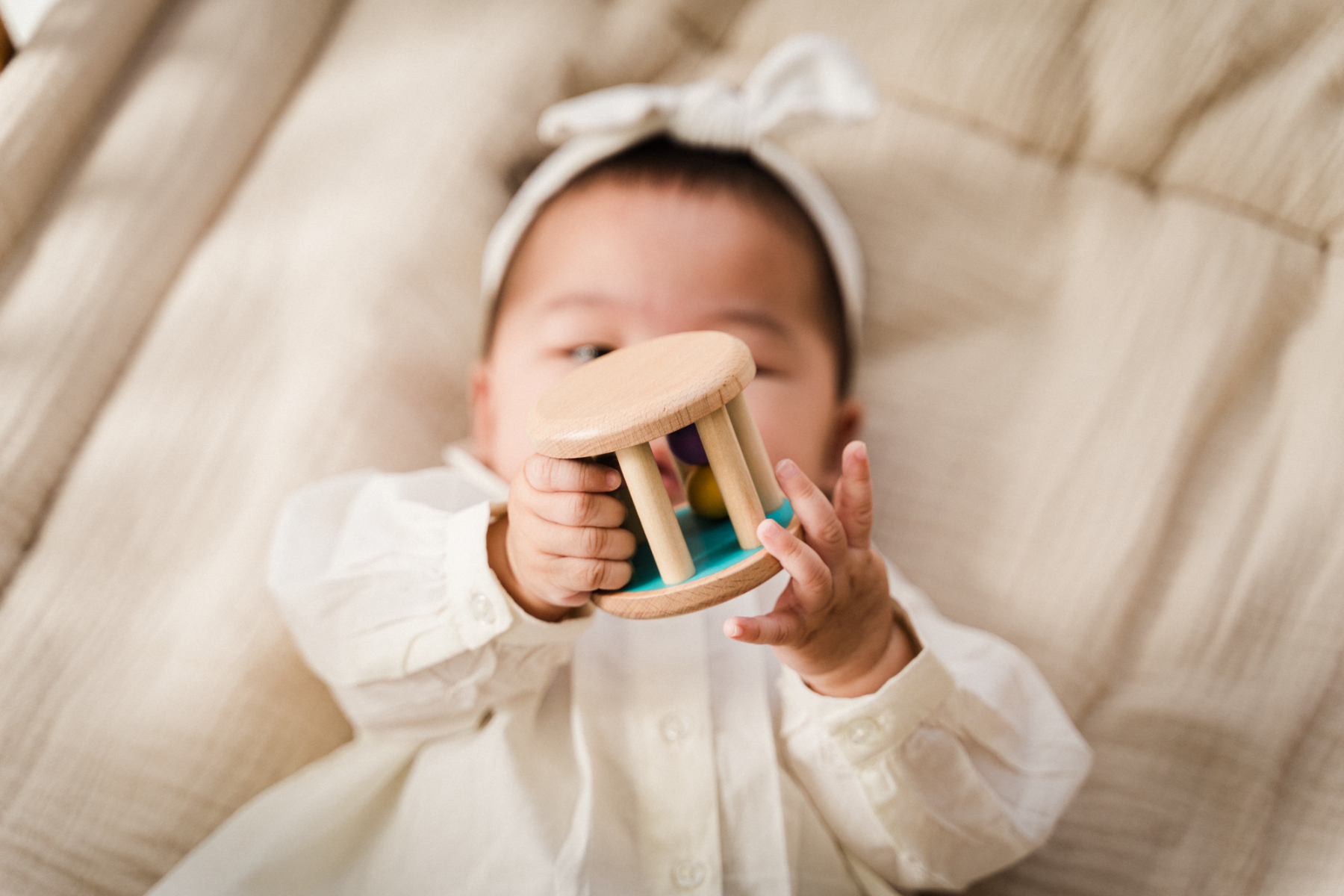 Bébé jouant avec un hochet en bois, développant la motricité fine et la coordination main-œil